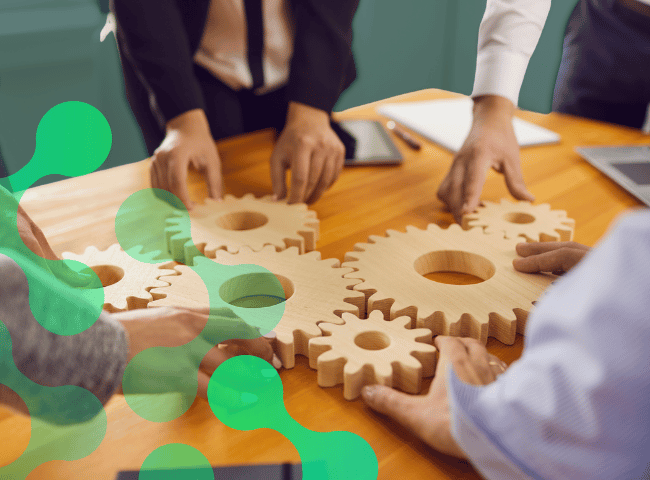 Cropped Image of Office Workers Attaching Wooden Gears to Each Other on a Desk in the Office