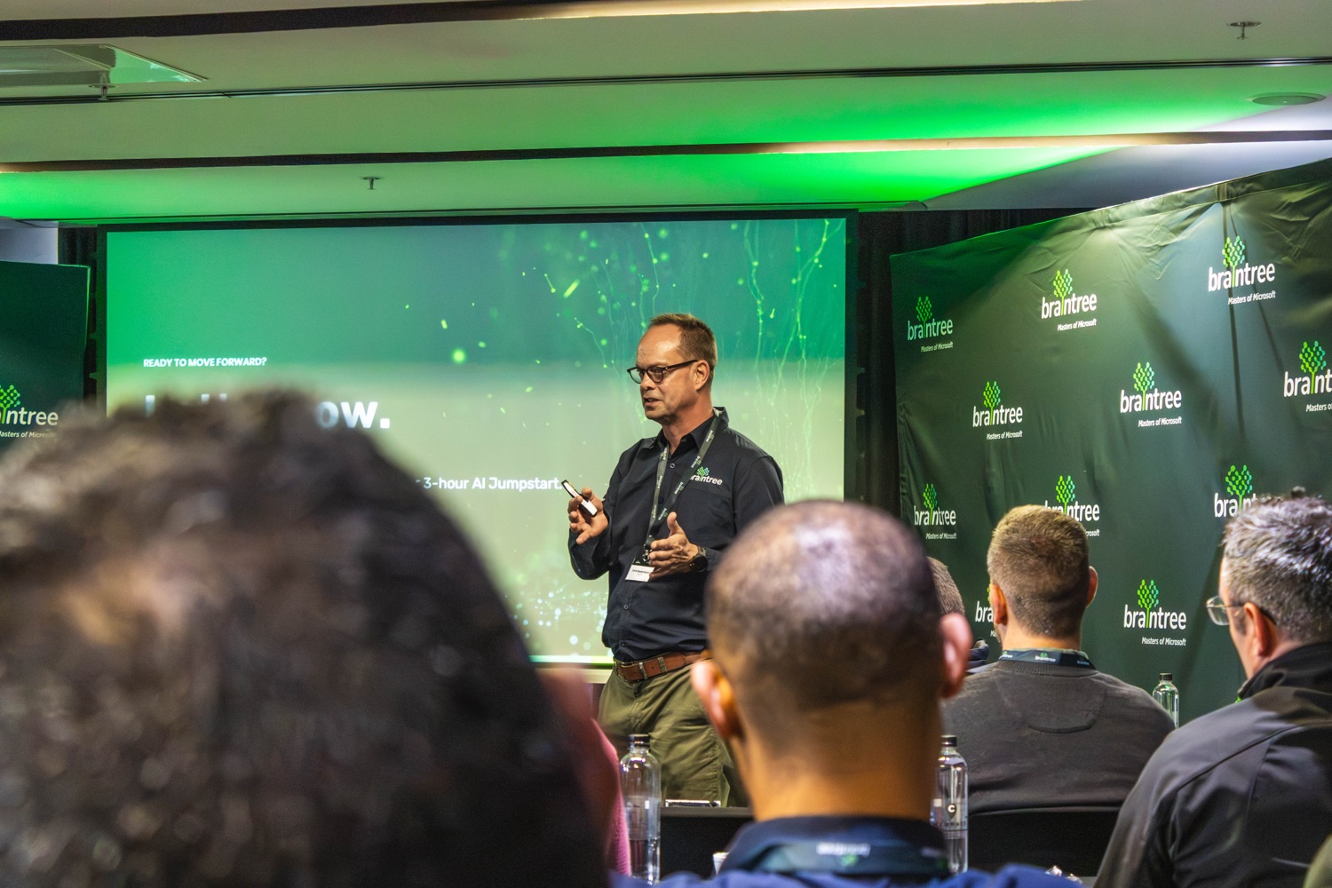 A presenter speaking to the room on the branded stage