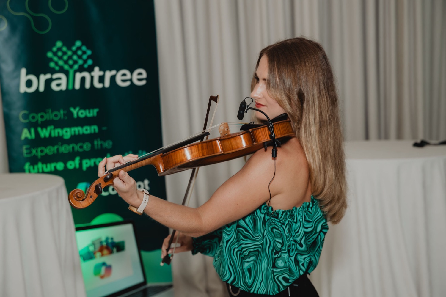 A violinist performing beside the Braintree Copilot banner