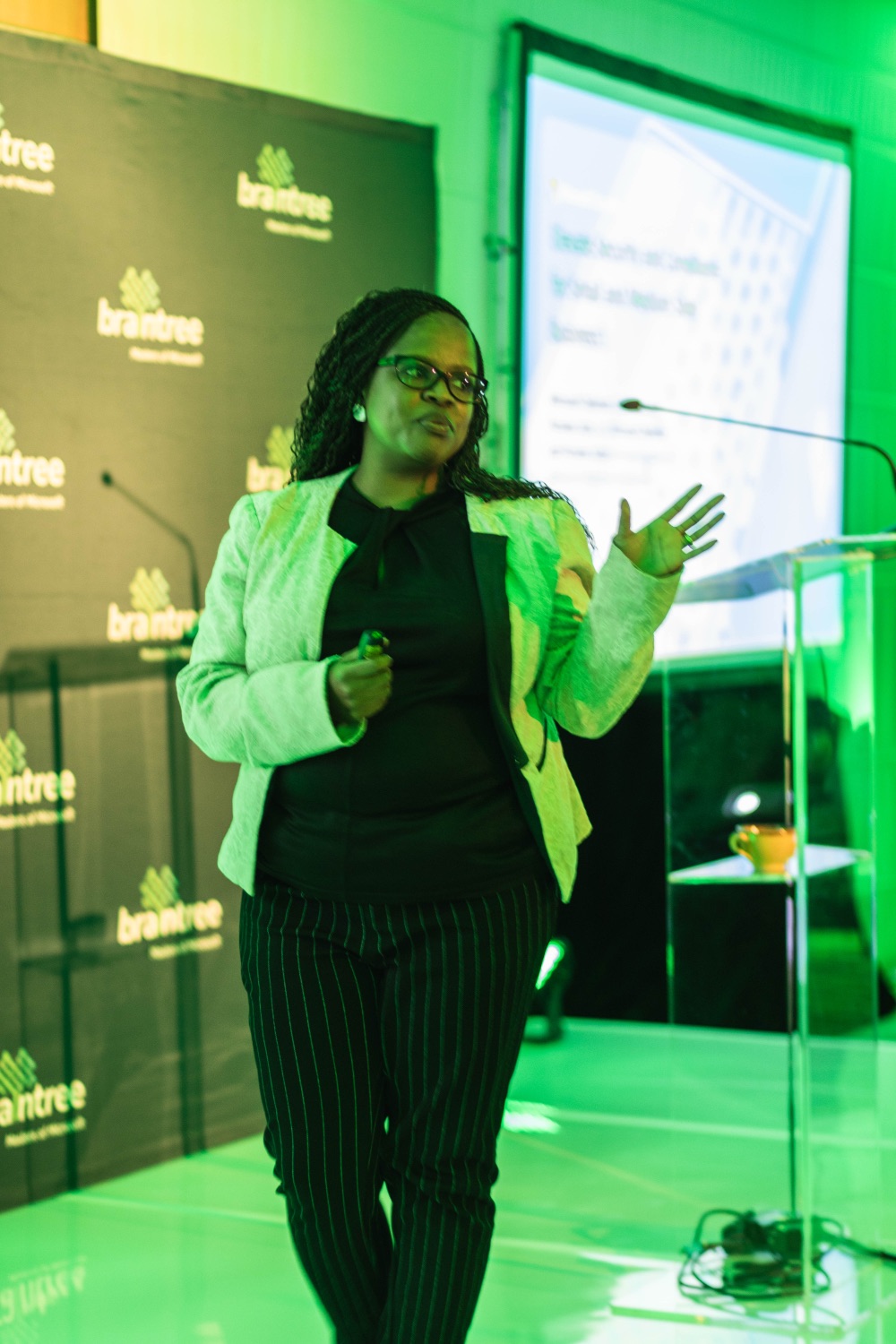 A speaker gesturing while presenting a slide to the audience