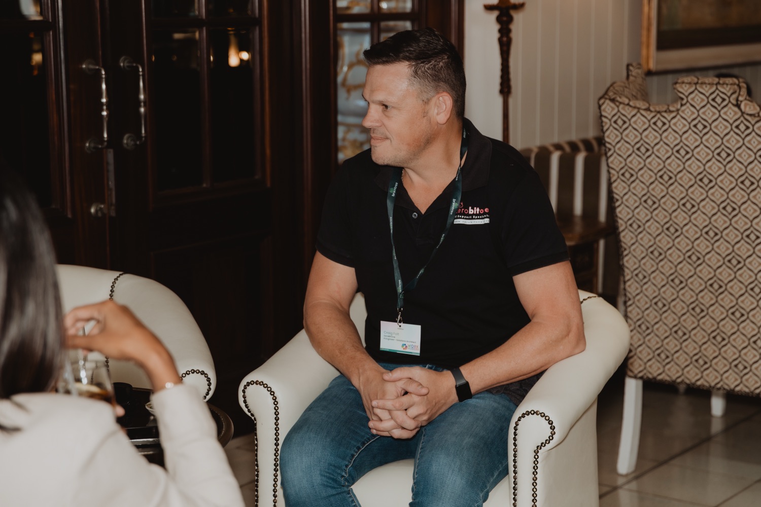 A guest with a lanyard smiling during a conversation