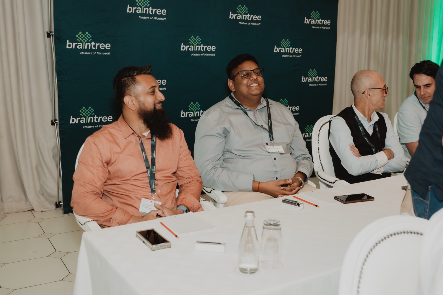 Guests smiling together at a table beneath the Braintree backdrop