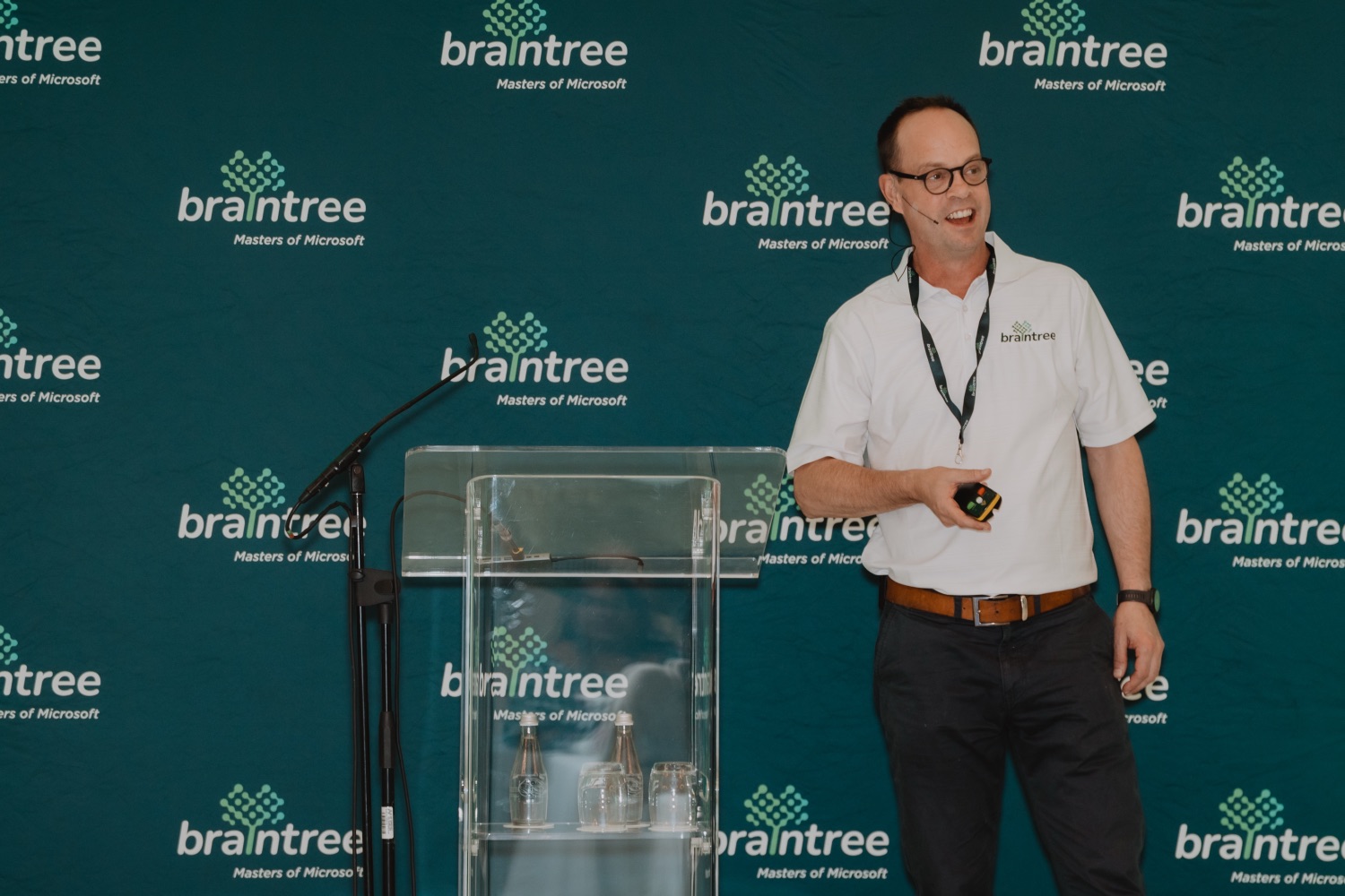 A speaker presenting at the podium in front of the branded backdrop