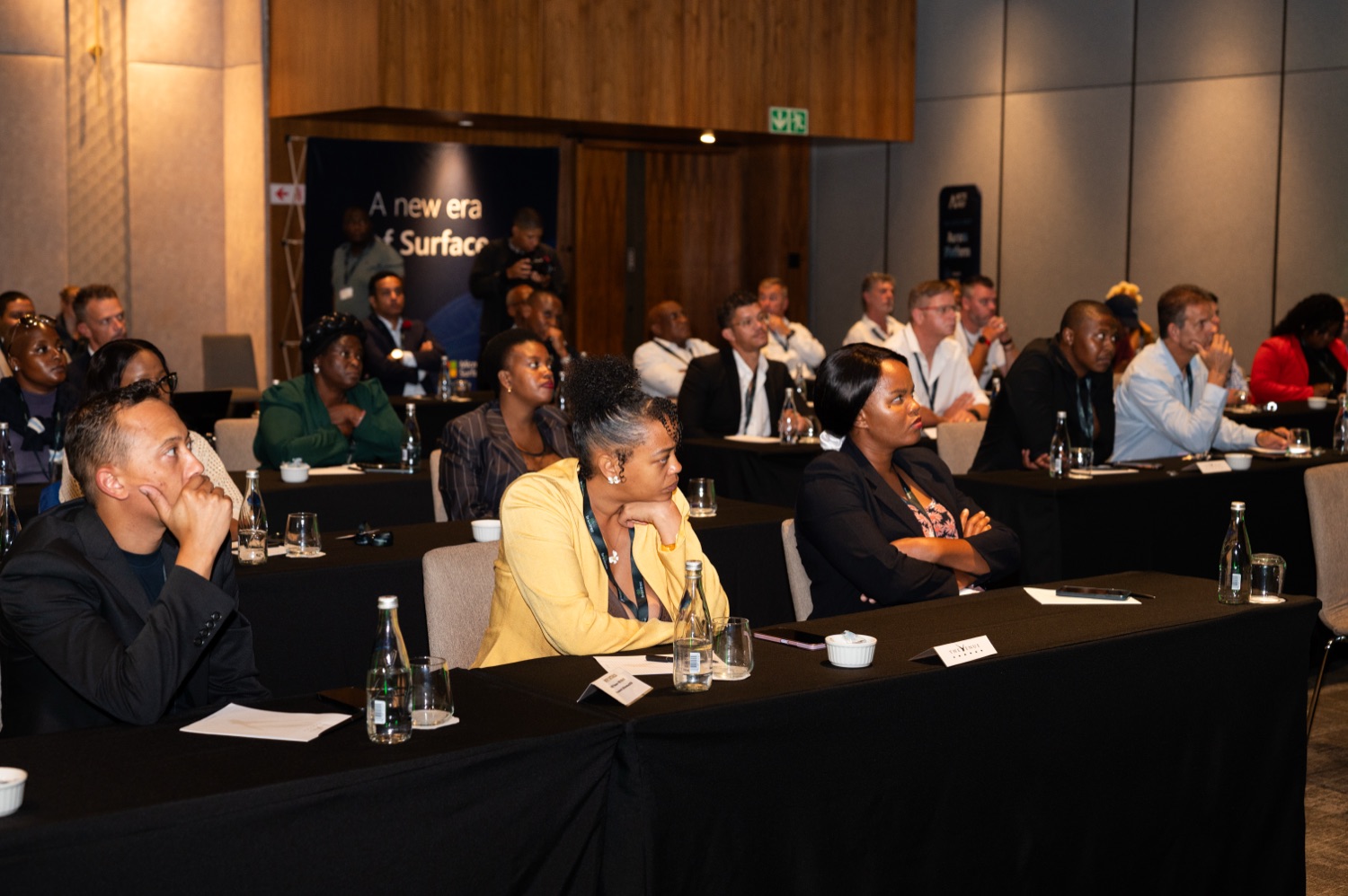 Attentive guests seated at tables watching a presentation during the session.