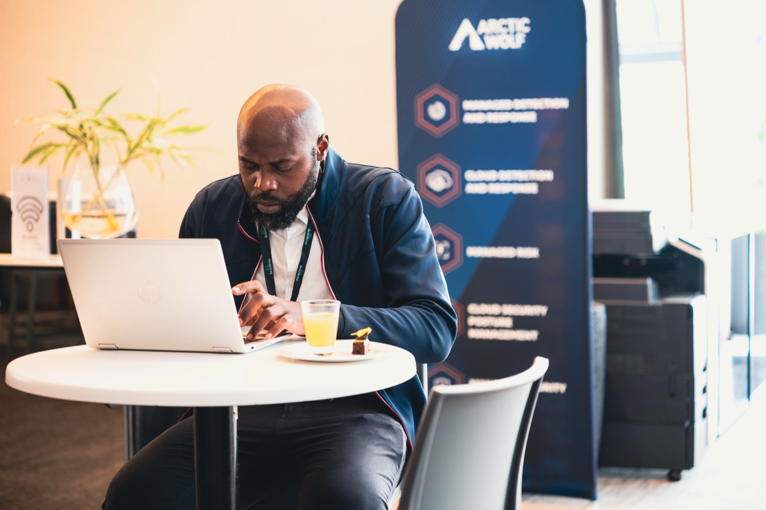 A guest working on a laptop beside the Arctic Wolf partner banner