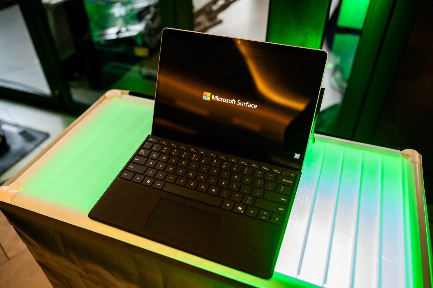 A Microsoft Surface device displayed on a green-lit plinth.