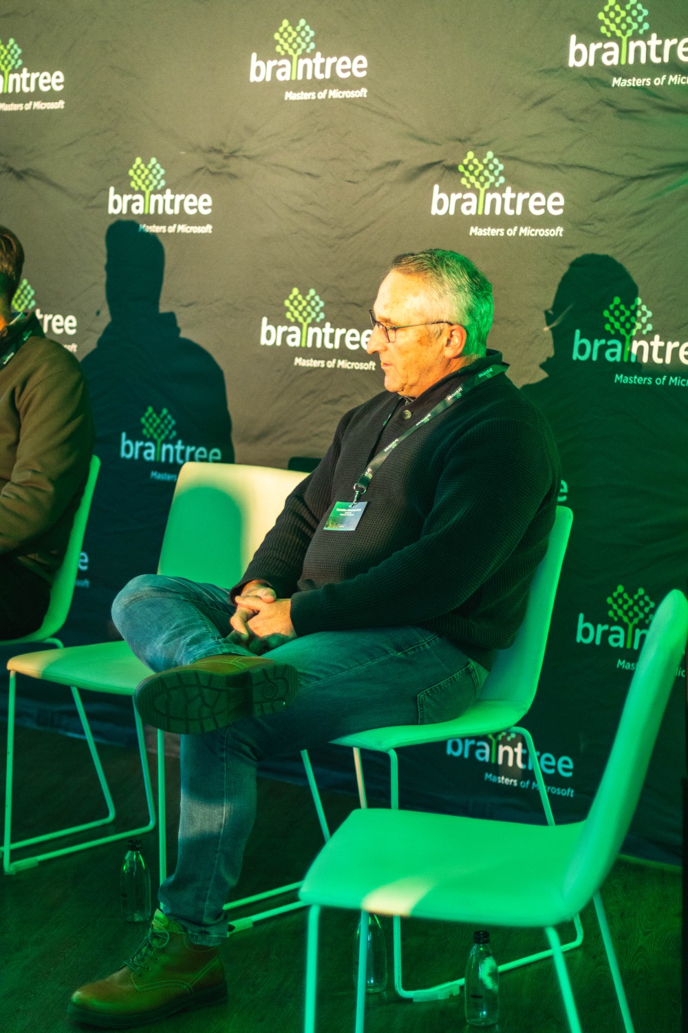A panellist listens during the fireside chat against the Braintree backdrop